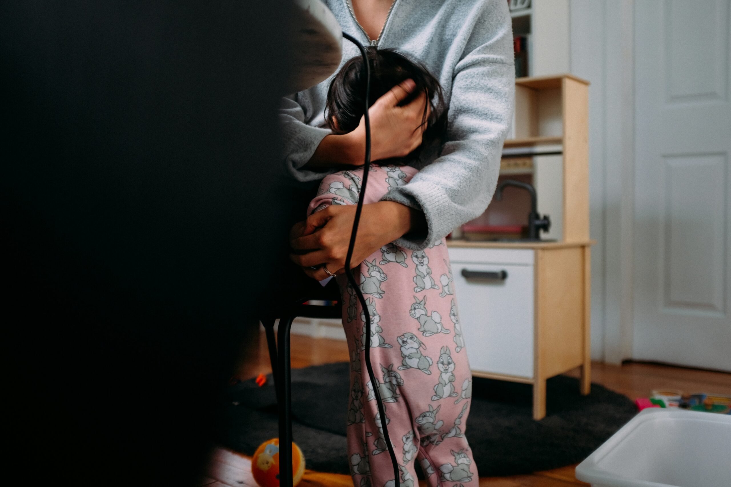A mother holding her young child in a cozy home setting, capturing the reality of work and parenting blending together and illustrating why traditional work–life balance isn’t realistic
